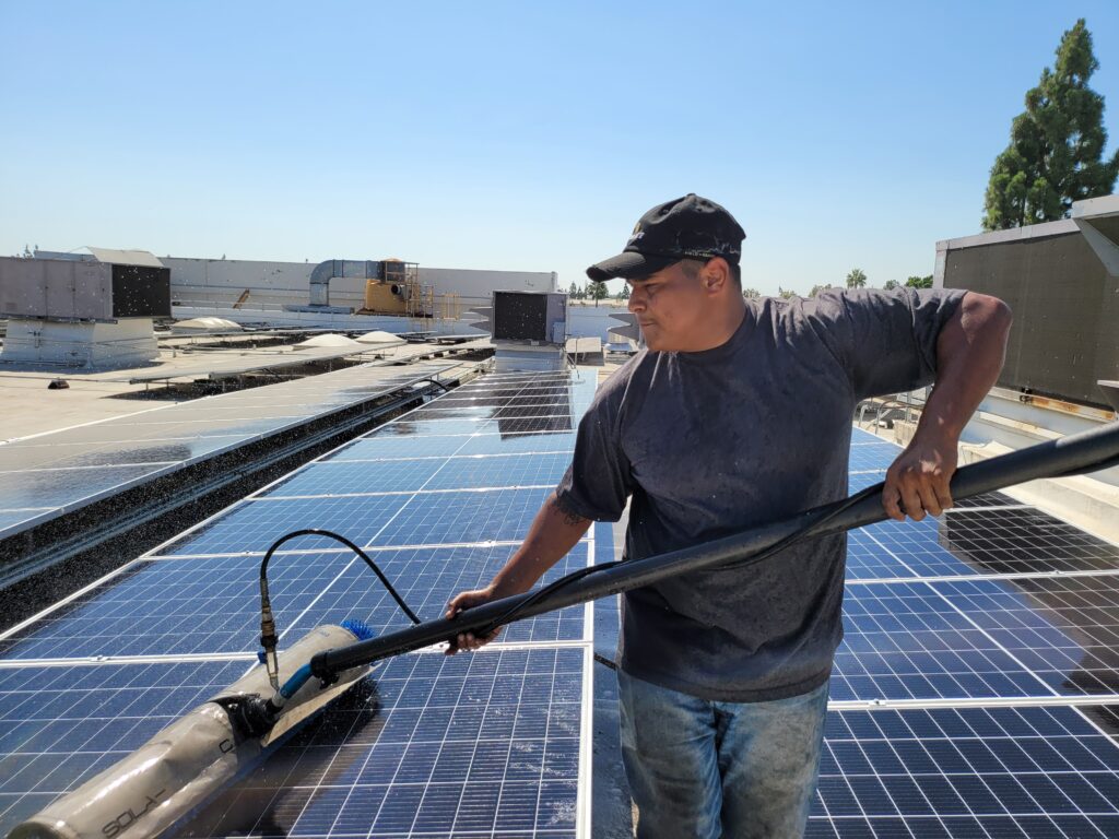 One of our staff cleaning solar panels with a solar panel cleaning brush